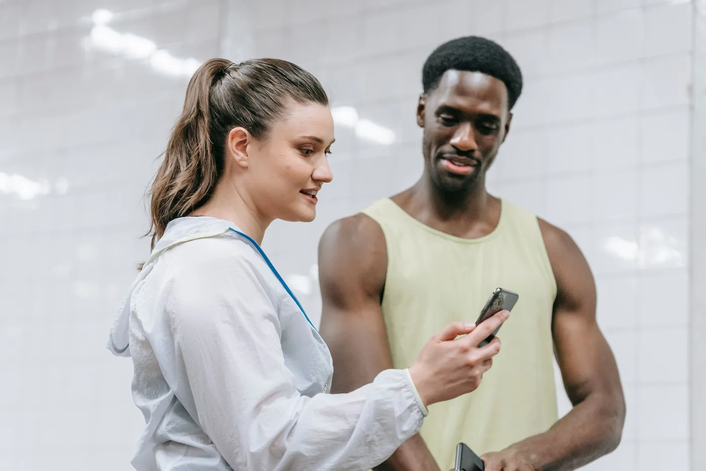 Entrenadora revisando en el celular el progreso de un socio dentro del gimnasio.